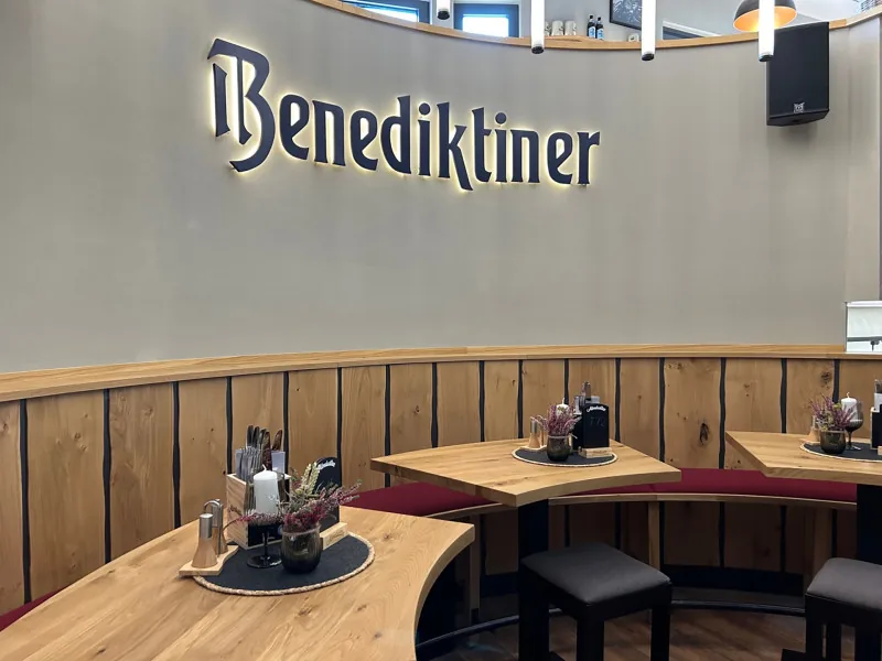 Geschwungene Sitzbank vor dem beleuchteten Benediktiner Schriftzug